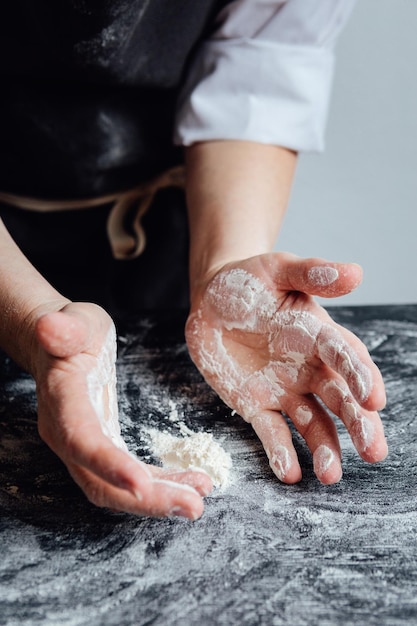 Hands of person picking odd flour on kitchen table Vertical studio shot