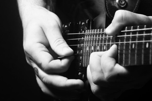 Hands of a person playing a guitar in black and white