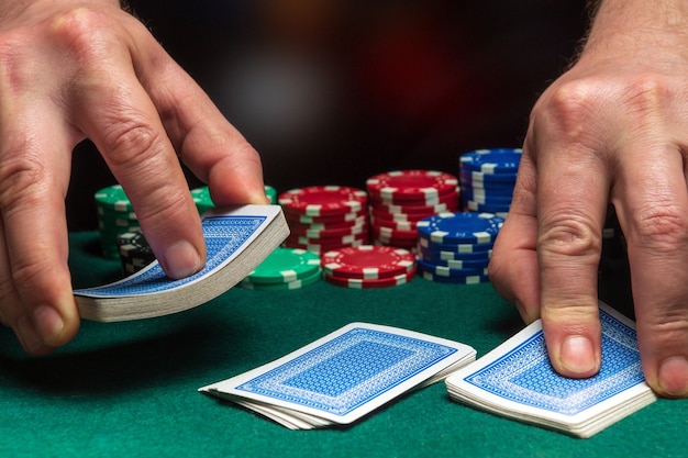 hands of persondealer or croupier shuffling poker cards in poker club on background of table