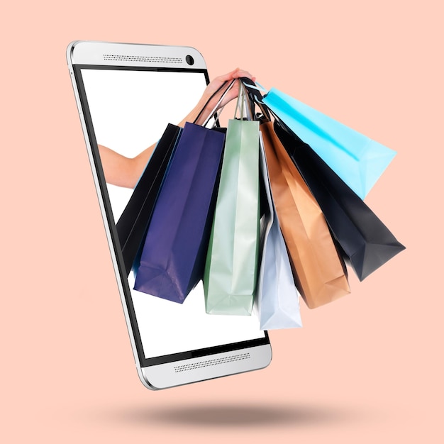 Hands phone and screen on mockup with shopping bags for purchase advertising or marketing against a studio background Hand of shopper with gifts on mobile smartphone display for online ecommerce