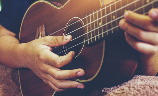 Mani che giocano la chitarra acustica delle ukulele. spettacolo di abilità musicali