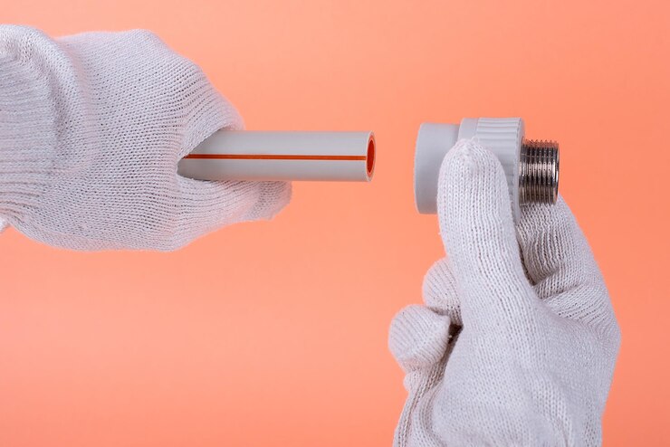 Hands of a plumber hold a plastic pipe on an orange background fixing and installation of plumbingxA