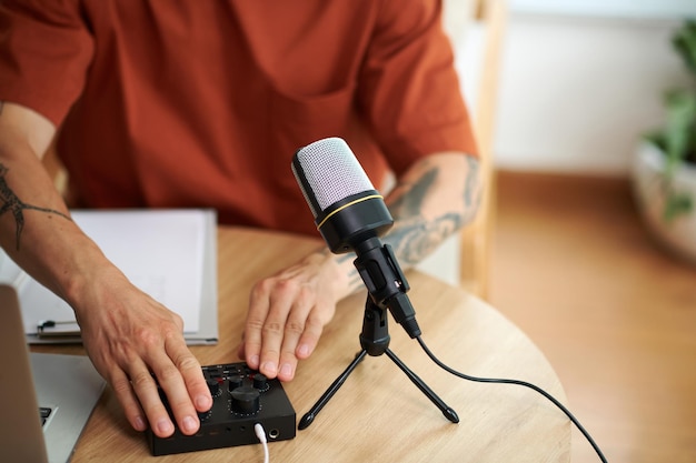 Hands of podcaster setting amplifier