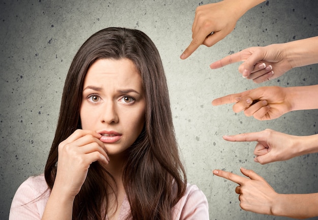 Hands pointing with fingers on thoughtful young woman looking at camera