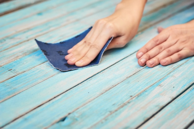 Mani che lucidano le assi di legno con una carta vetrata