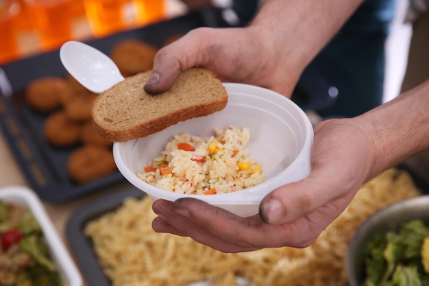 Hands of poor man holding bowl with rice and bread Poverty concept