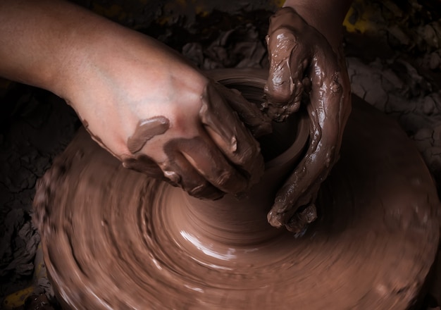 hands of a potter, creating an earthen jar on the circle