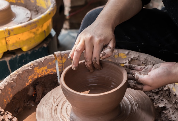 Photo hands of a potter, creating an earthen jar on the circle