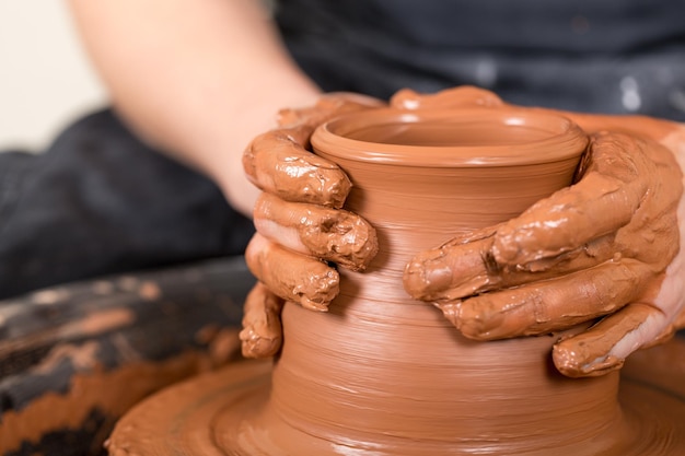 Hands of potter making clay pot, closeup photo