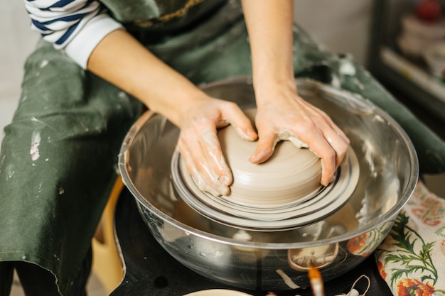 Hands of potter making clay pot on potter's wheel