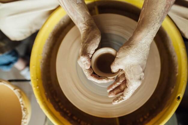 Hands of a potter potter making ceramic pot on the pottery wheel