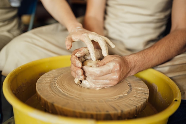 Mani di un vasaio che fa un vaso di ceramica sul tornio