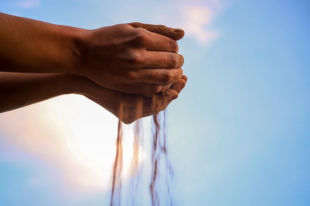 Hands pouring the soil with a blue sky behind them