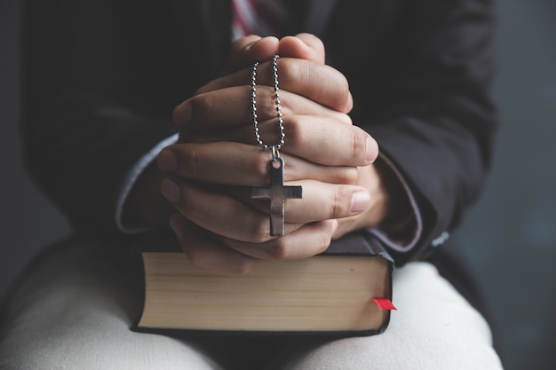 Photo hands of praying young man and bible desk