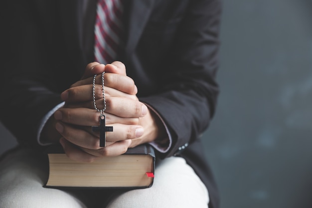 祈る若い男と聖書の机の手