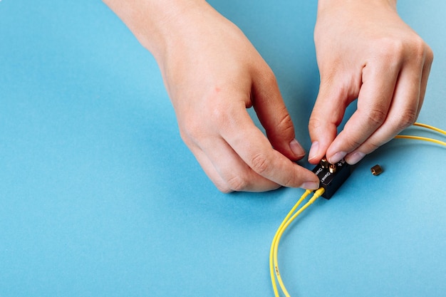 Hands prepare to tune a variable optic attenuator with a screwdriver Blue background