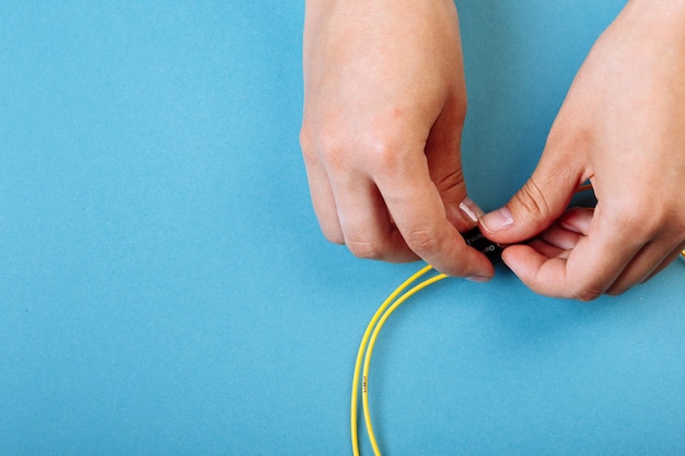 Hands prepare to tune a variable optic attenuator with a\
screwdriver blue background