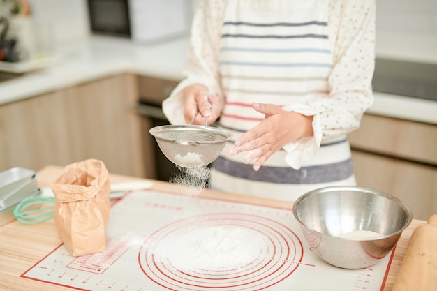 Hands preparing bread dough on wooden table.