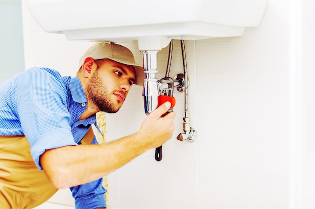 Hands of Professional plumber fixing pipes. Plumbing repair service.