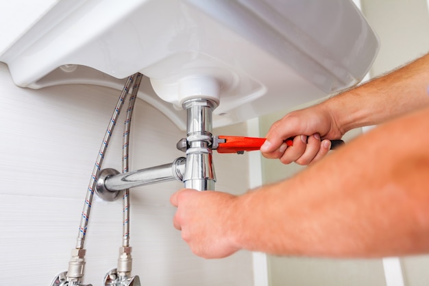 Hands of Professional plumber fixing pipes. Plumbing repair service.