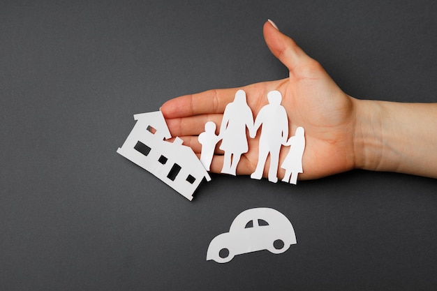 Photo hands protecting a family; symbol of life insurance on black background