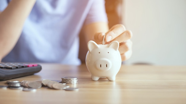 Photo hands put money coin into piggy bank for saving money wealth