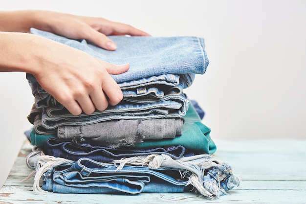 Hands, put the stack of blue jeans on white backgroundHands, put the stack of blue jeans on white background