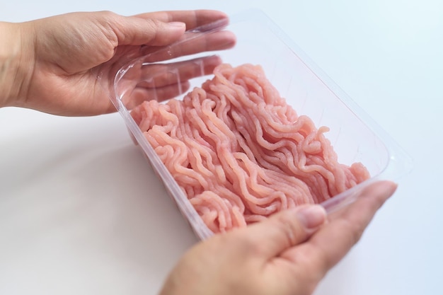 Hands put on a white table a plastic package with fresh minced meat