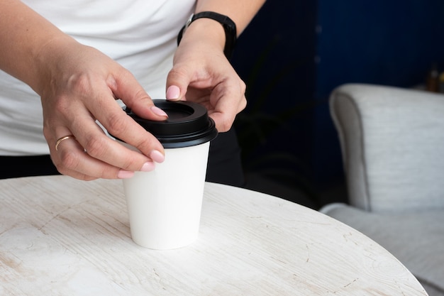 hands putting a black lid on a white paper cup