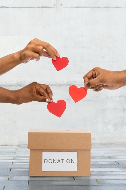 hands putting hearts into donation box on street