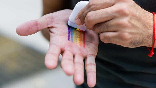 Hands putting on rainbow makeup to celebrate gay pride month.