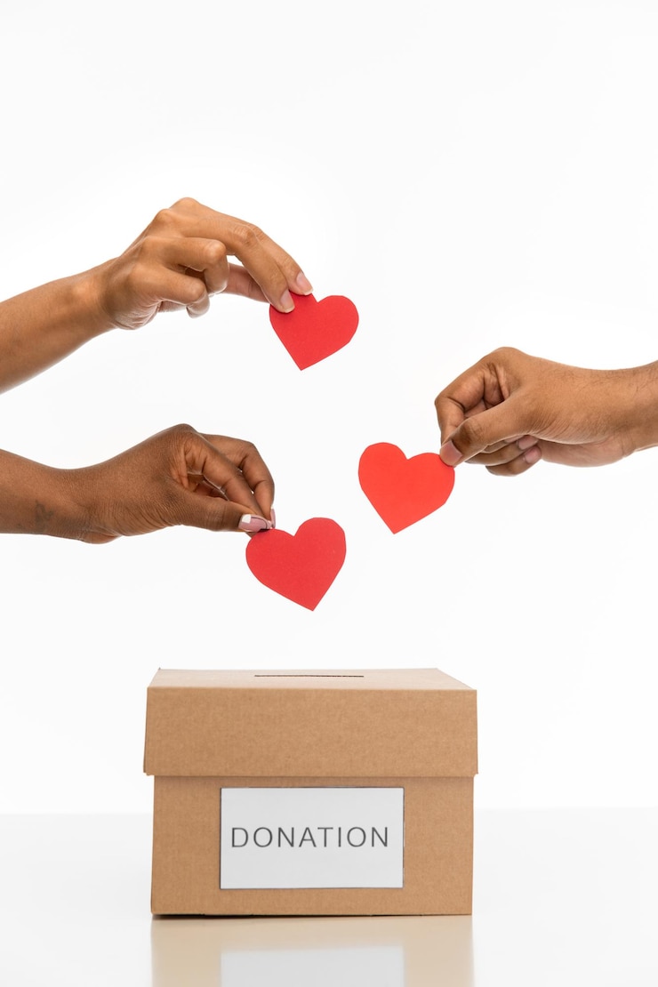 Photo hands putting red heart into donation box