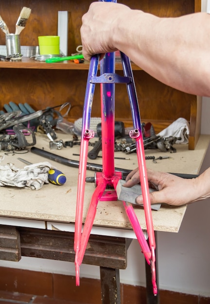 Hands of real bicycle mechanic sanding frame bike