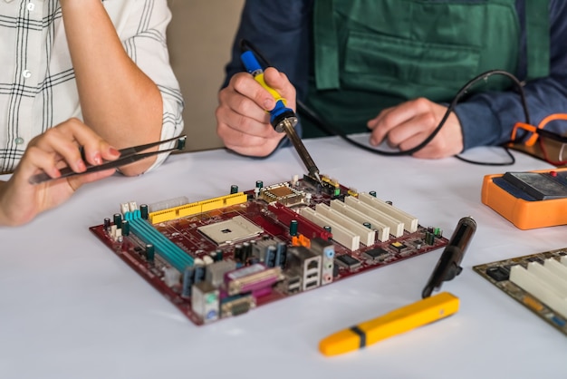 Hands repairing computer motherboard by soldering