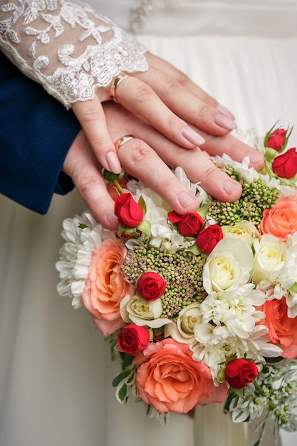 Hands and rings on wedding bouquet