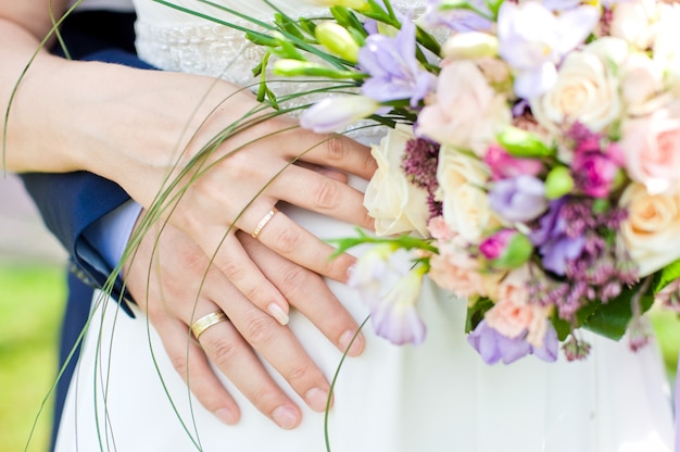 Hands and rings on wedding bouquet