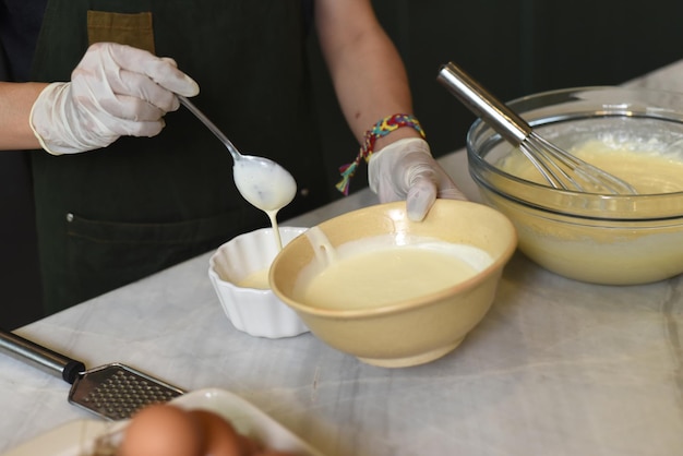 Mani in guanti di gomma che mescolano il tuorlo in una ciotola