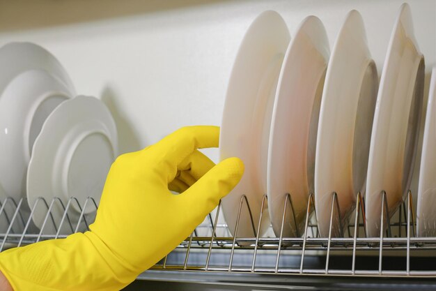 Photo hands in rubber protective gloves put the plate in the kitchen cabinet cleaning service closeup