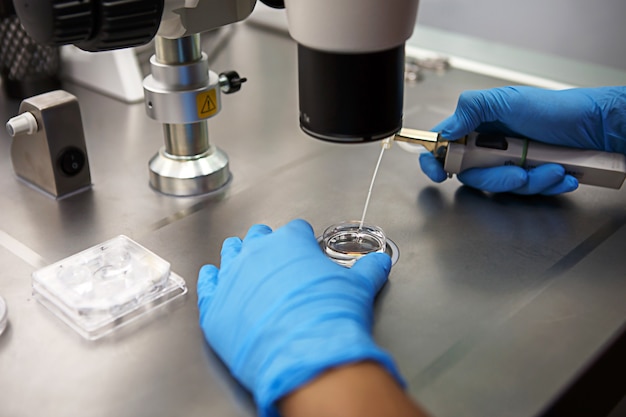 Hands of a scientist in the laboratory with a test tube and a microscope.