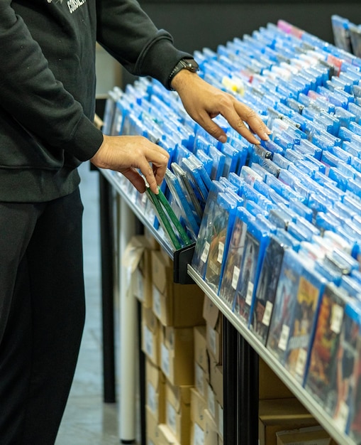 Hands searching and choosing movies and dvds on a shelf in a movie collector's store and merchandising sale of movie discs