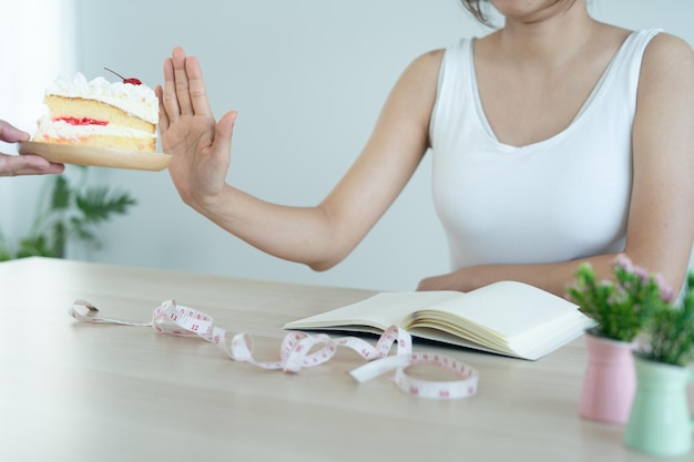 Hands sends plate of cake to slim women The woman pushed the plate the cake and refused to eat sweets and fat people Health Care and diet concept