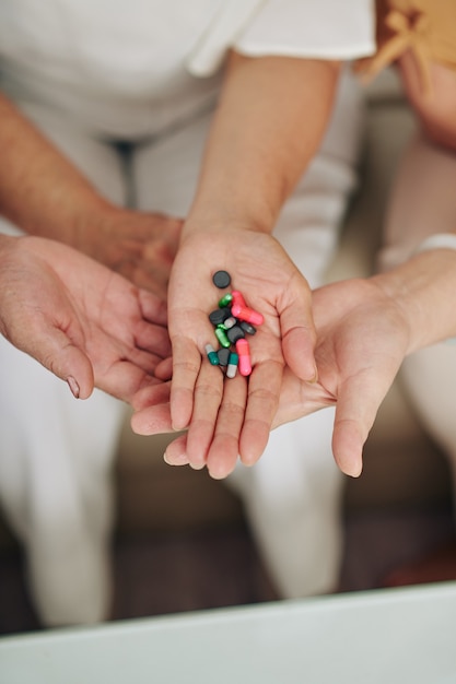 Hands of senior women holding pills, supplements and vitamins