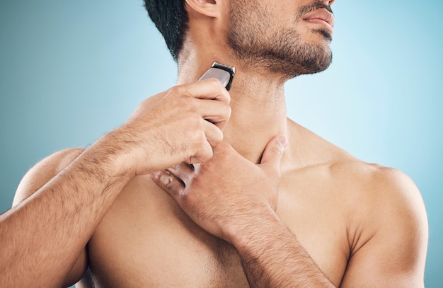 Hands shaving and electric razor with a man in studio on a blue background for personal hygiene or grooming Beauty wellness and cosmetics with a young male in the bathroom for hair removal