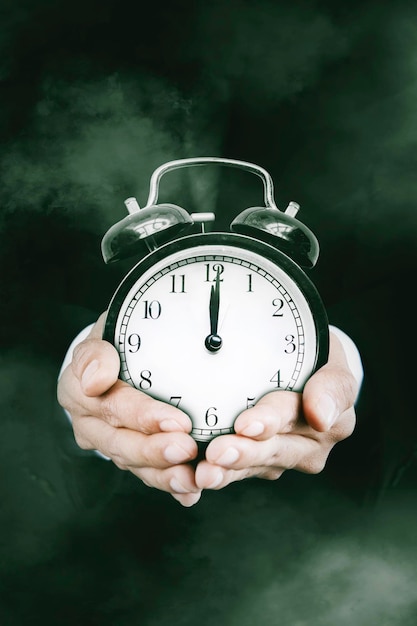 Hands showing an alarm clock in the dark room