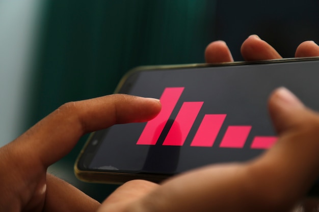 Photo hands showing decrease graph on a smart phone