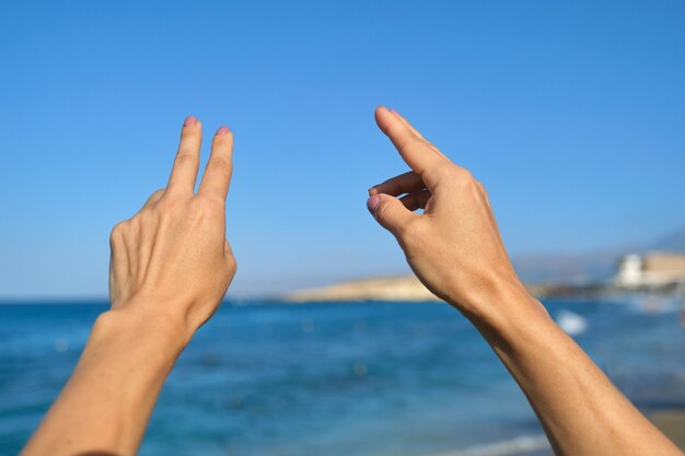 Photo hands showing finger gesture, blue sky sea space