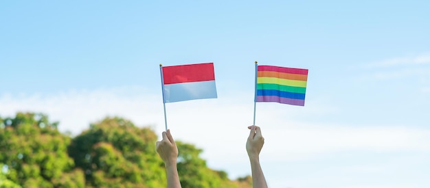 자연 배경에 LGBTQ 레인보우와 인도네시아 국기를 보여주는 손 레즈비언 게이 양성애자 트랜스젠더 및 퀴어 커뮤니티 및 프라이드 월 개념 지원