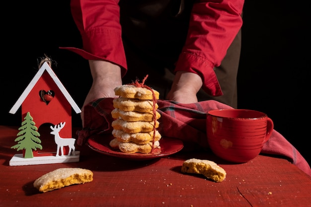 Hands shows Biscuits on Red Wooden table with Red Cup of coffee and New Year Toy