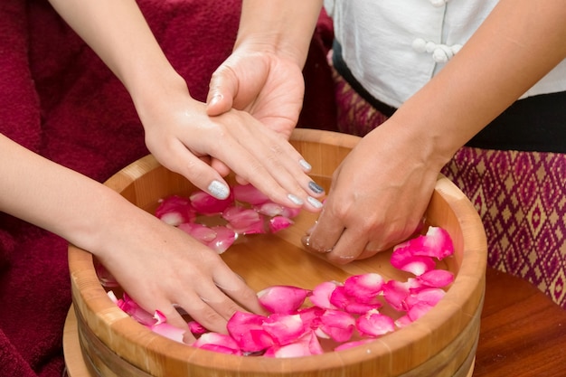 Manicure della stazione termale delle mani in ciotola di legno con i petali di rosa