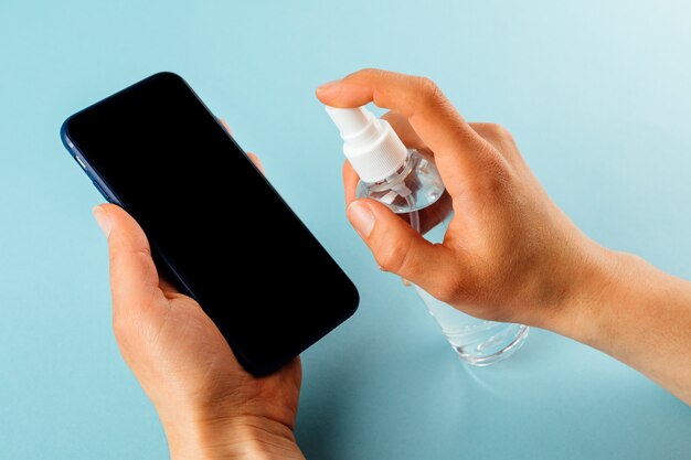 Hands spraying sanitizer on a phone